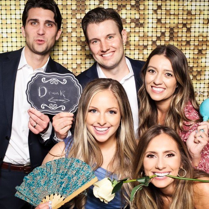 A group with a chalkboard sign and fan on the gold sequin wall