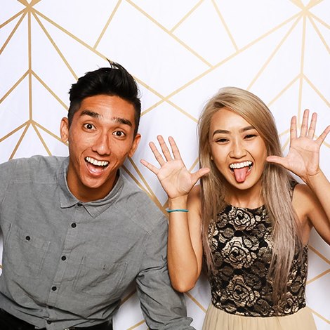 A couple waving on the white and gold geometric backdrop