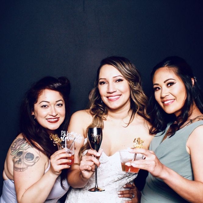 A woman in white and her friends raising champagne on a black backdrop