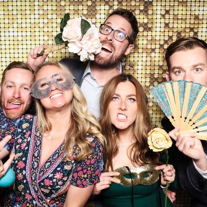 A group with fans, roses and masks on the gold sequin wall