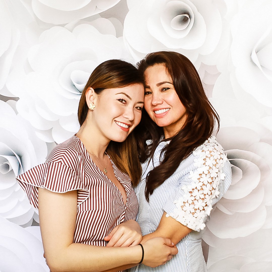 Two friends posing in front of a white paper-rose wall