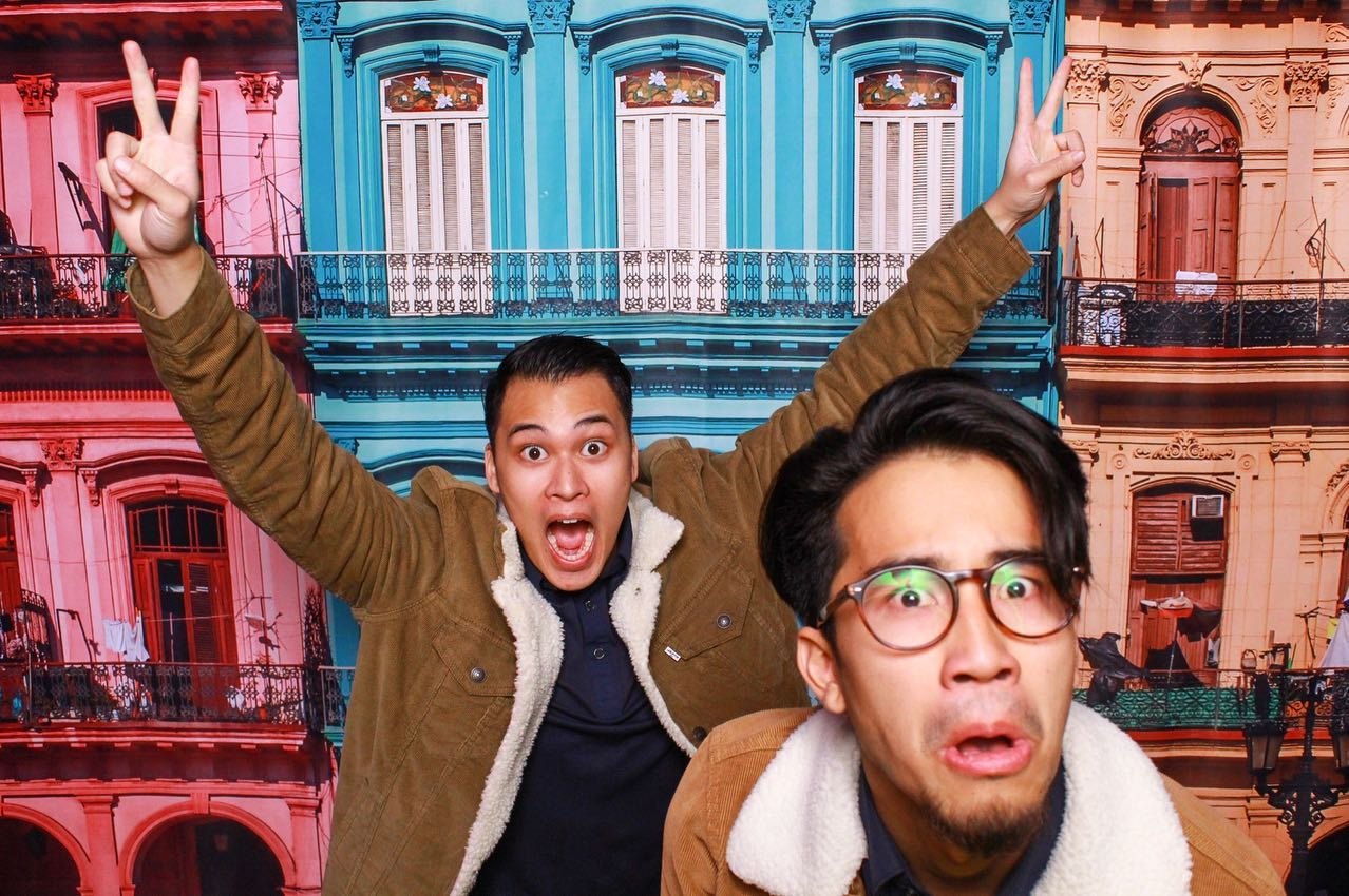 Two friends in front of a colourful street-facade scene